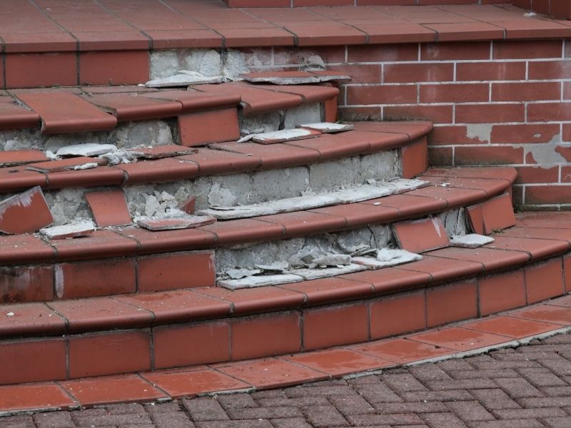 Masonry contractor inspecting brick cracks on a residential home's exterior after foundation repairs in McKinney, Texas.
